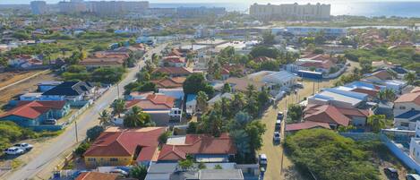 Un barrio residencial con casas, caminos y una playa al fondo.