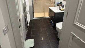 Un bany modern amb una cabina de dutxa de vidre, un lavabo blanc i un vàter.