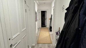 Un passadís amb portes blanques, un sòl de fusta i un penjall de cabells a la dreta.