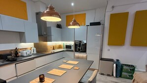 Una cuina moderna amb una illa central, il·luminació penjant i una zona de menjador.