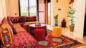 Ein gemütliches Wohnzimmer mit einer Couch, einem Hocker und einem gemusterten Teppich.