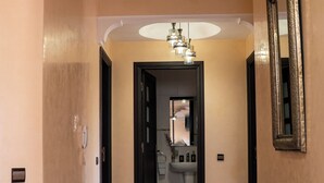 Ein Flur mit rotem Teppichmuster, einem Chandelier und einem Spiegel an der Wand.