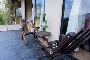 A seating area with wooden chairs and a small round table, a vase with flowers, and a view of greenery and a building through a glass door. - Hotel Campestre Rancho La Lechería (Cali)