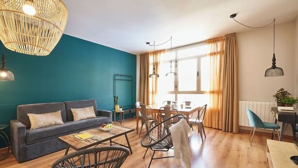 A modern living room with a sofa, coffee table, and dining area. - Family apartment in Sants (Barcelona)