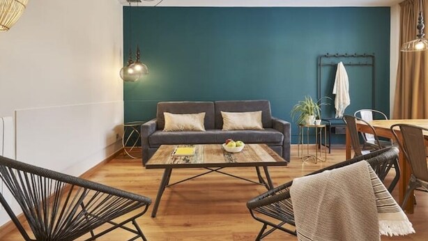 A cozy living area with a sofa, coffee table, and chairs, a dining table with chairs, and a wall-mounted radiator.