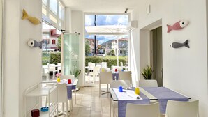 A bright dining area with white furniture, a view of the outside, and decorative fish on the walls. - Residence with panoramic swimming pool in Porto San Paolo just 850 mt from the sea (Porto San Paolo)