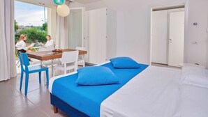A modern hotel room with a large bed, a dining area, and a view of the outdoors. - Residence with panoramic swimming pool in Porto San Paolo just 850 mt from the sea (Porto San Paolo)