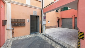 Une ruelle étroite, fermée par un portail métallique, avec une boîte aux lettres et un panneau indiquant qu’il est interdit de se garer.