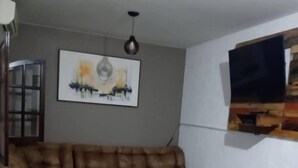 Un salon comprenant un canapé d’angle, un téléviseur à écran plat fixé au mur et une œuvre d’art encadrée au-dessus du canapé.