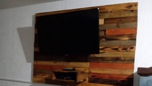 Un téléviseur fixé au mur, doté d’un design avec un panneau en bois.