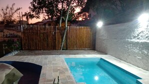 Une piscine dotée d’une terrasse carrelée, entourée d’une clôture en bois et d’un mur.