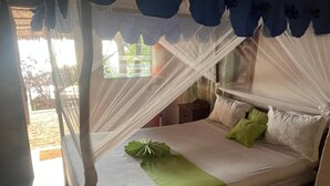A bed with a canopy, a green pillow, and a white pillow. - Villa Maroloko (Ifaty)