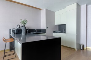 Eine moderne Küche mit einer großen Kochinsel, Barhocker und einer Vase mit Grünpflanzen.