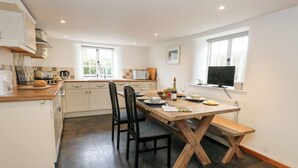 A modern kitchen with a dining table, chairs, and a TV. - Bubbs Cottage (Dorchester)