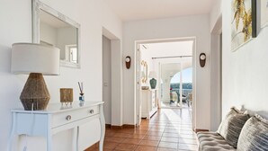 Ein Flur mit einer weißen Konsole, einer Lampe, einem Spiegel und einem Sofa.