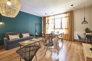 A modern living room with a sofa, coffee table, and dining area. - Big & spacious 3BR flat in Sants (Barcelona)