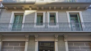 Une façade d’immeuble avec un balcon, une porte portant l’inscription « 3-5 », et les mots « APARTMENTS BARCELONA » écrits sur les murs.