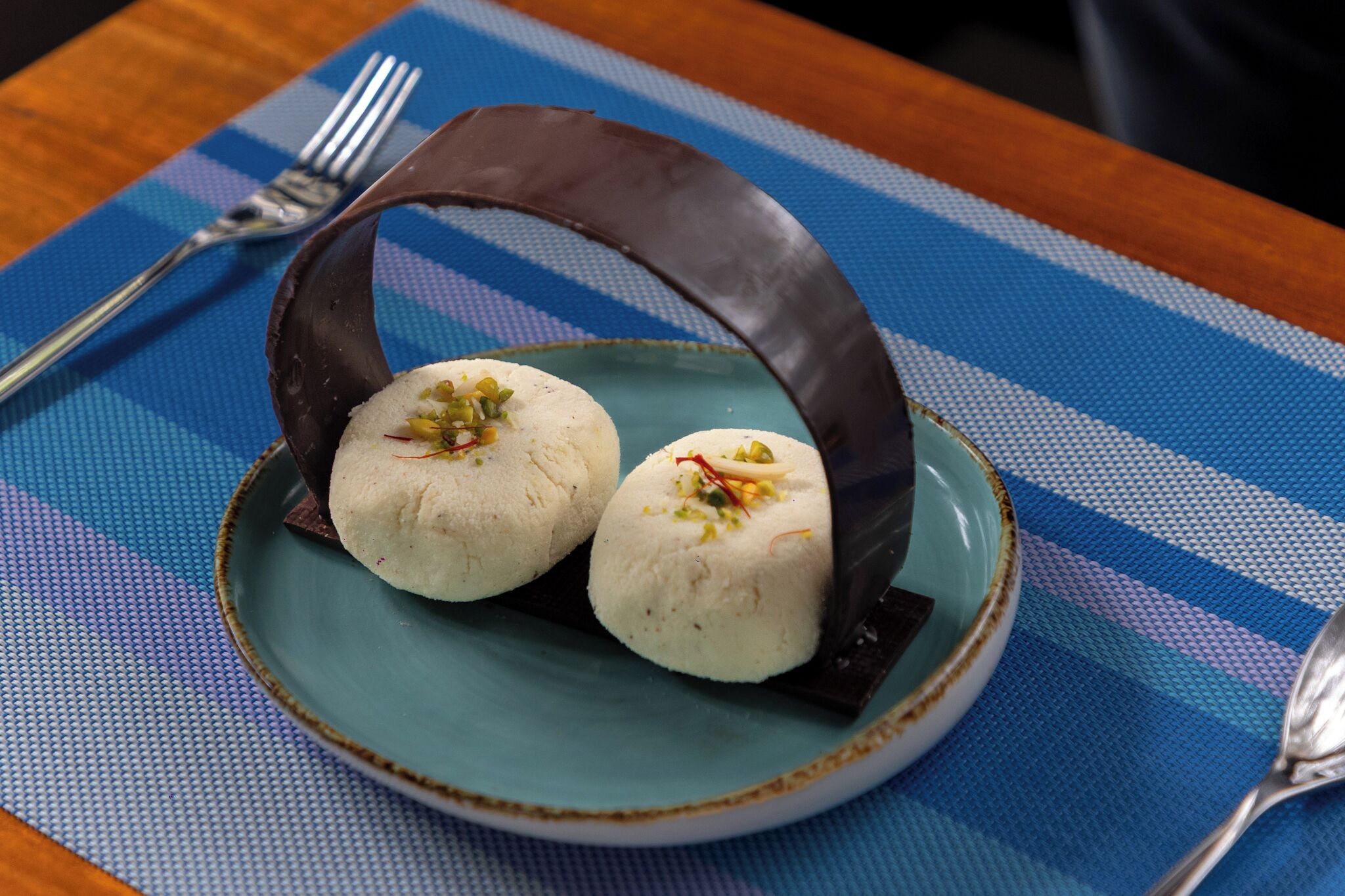Un plato con dos postres blancos sobre un camino de mesa azul y blanco a cuadros.