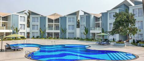 A modern hotel with a swimming pool, sun loungers, and a landscaped garden.