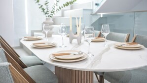Ett modernt matområde med ett bord i marmor, grå klädda stolar och en minimalistisk inredning.