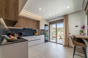 Eine moderne Küche mit schwarzer Arbeitsplatte, Holzschränken und Blick auf einen Balkon mit Sitzgelegenheit.