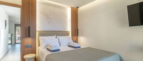 A modern bedroom with a bed, a bedside table, a wall-mounted TV, and a marble-patterned wall.