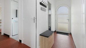 En hall med en vit dörr, en klädhängare och en liten bänk.