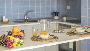 Una cocina con un lavabo, una cesta de frutas, una jarra y un plato con un pastel.