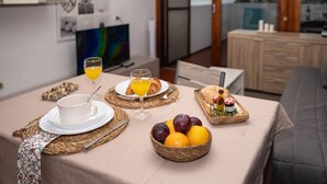 Desayuno con fruta, croissants y zumo de naranja sobre una mesa, con vista a la ciudad al fondo.
