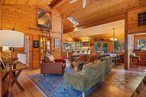 A spacious log cabin interior with a living room, kitchen, and dining area.