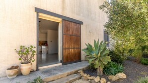 A modern house with a wooden door, potted plants, and a gravel pathway leading to the entrance. - Villa Silvia with Swimming Pool by Wonderful Italy (Noto)
