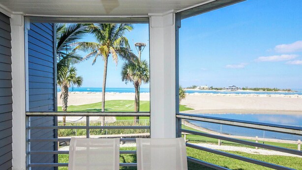 Un balcón con vista a una playa, palmeras y un campo de golf.