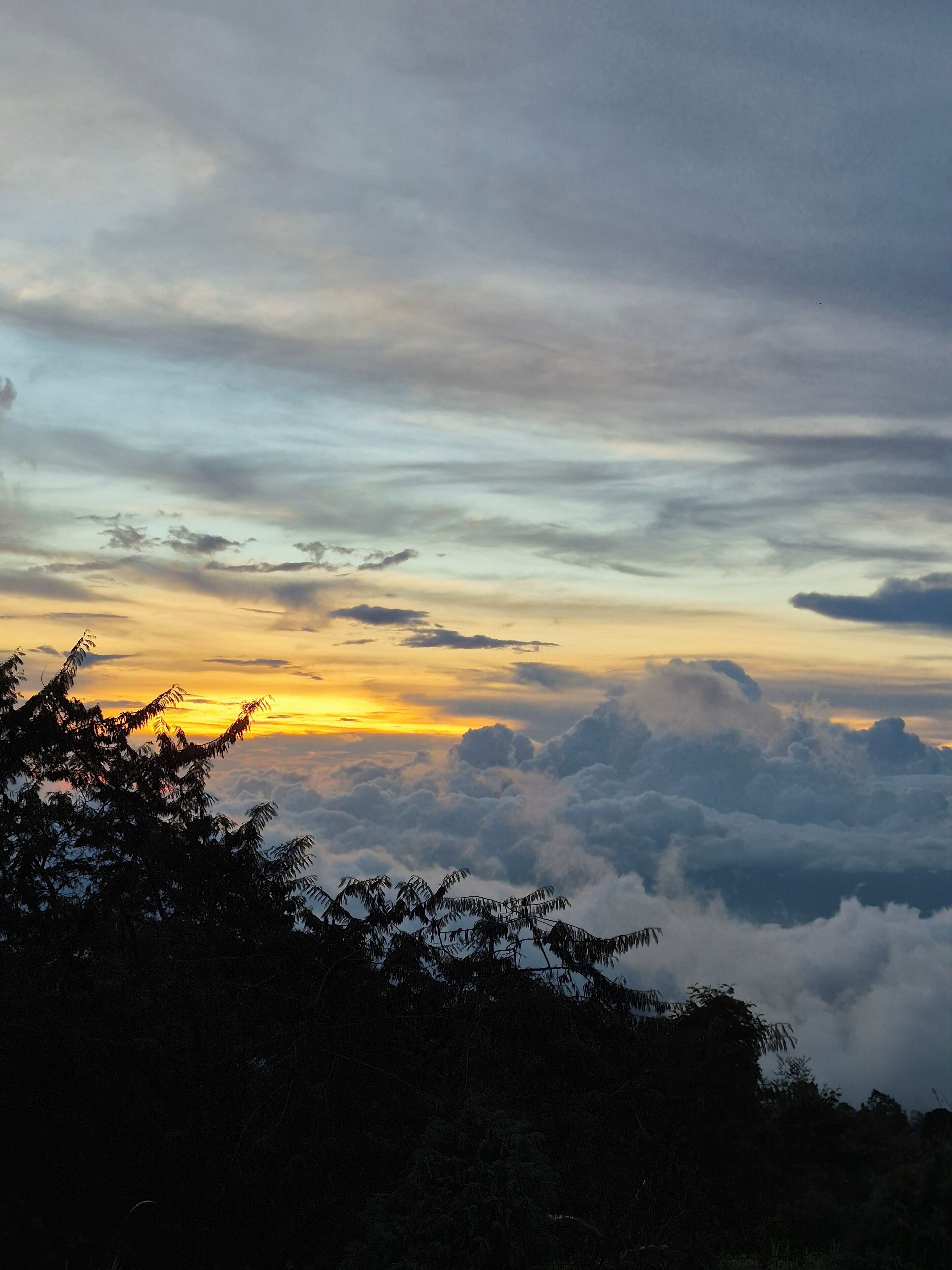 A view of a mountainous landscape with a sunset and clouds.