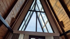 Ein Zimmer mit schrägen Wänden, Holzbalken und einem großen Dachfenster.