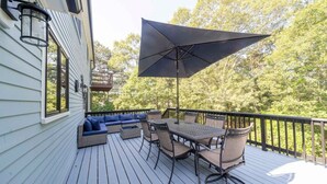 Eine Terrasse mit Esstisch und Stühlen, einer Sitzecke und einem großen Sonnenschirm.