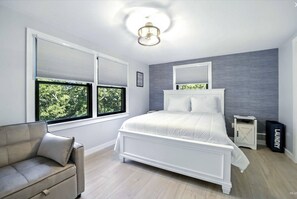 A bedroom with a bed, a chair, a nightstand, and a laundry basket. - Welcome to Plaisir d’Amour — “The Pleasure of Love”!  Sleeping 10! (Dennis)