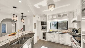 Eine moderne Küche mit weißen Schränken, Granit Arbeitsplatten, Edelstahlgeräten und Pendelleuchten.