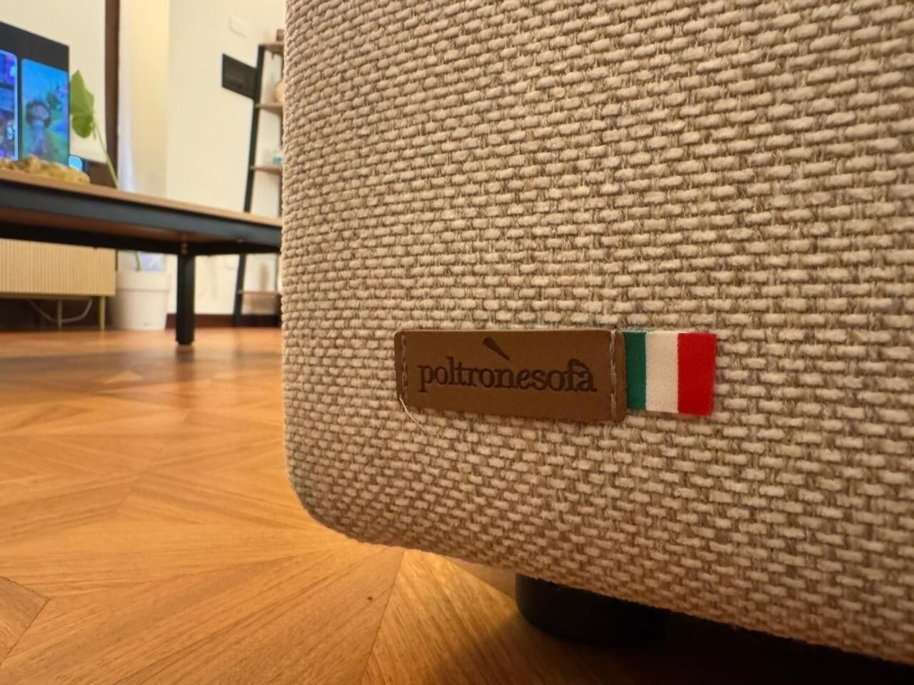 Un pouf à texture tissée, orné d’une étiquette indiquant « poltronesofa » et d’un petit drapeau italien.
