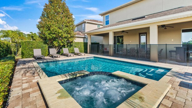 A swimming pool with a hot tub, lounge chairs, and a covered patio area. - Pool Table, Arcade, Foosball, Resort-style Pool: Sunny Villa (Kissimmee)