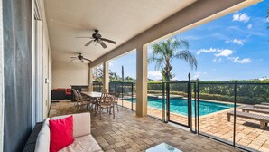 A covered patio with a pool, outdoor furniture, and a view of the surrounding landscape. - Pool Table, Arcade, Foosball, Resort-style Pool: Sunny Villa (Kissimmee)