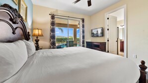 A hotel room with a large bed, a ceiling fan, a balcony with a view, and a television on the wall. - Pool Table, Arcade, Foosball, Resort-style Pool: Sunny Villa (Kissimmee)