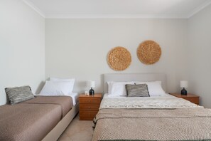 Ein Hotelzimmer mit zwei Betten, einem hölzernen Nachttisch, einer Wandlampe und einem gewebten Wandbild.