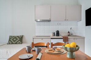 A compact kitchen with white cabinets, a coffee maker, and a bowl of fruit on the counter. - Apartment 'One Bedroom  6' with Sea View, Wi-Fi and Air Conditioning (skoutari)