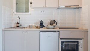 Eine kompakte Küche mit integriertem Geschirrspüler, einer Kaffeemaschine und einer Mikrowelle.