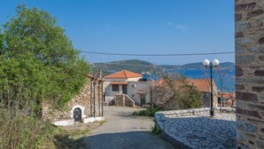 Ein Steinhaus mit einem Ziegeldach, einem Kopfsteinpflasterweg und Blick auf das Meer.