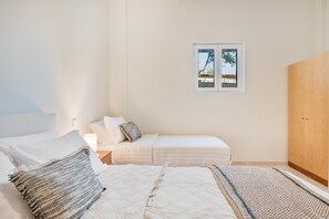 Un dormitorio con una cama, una mesita de noche, una ventana y un armario.