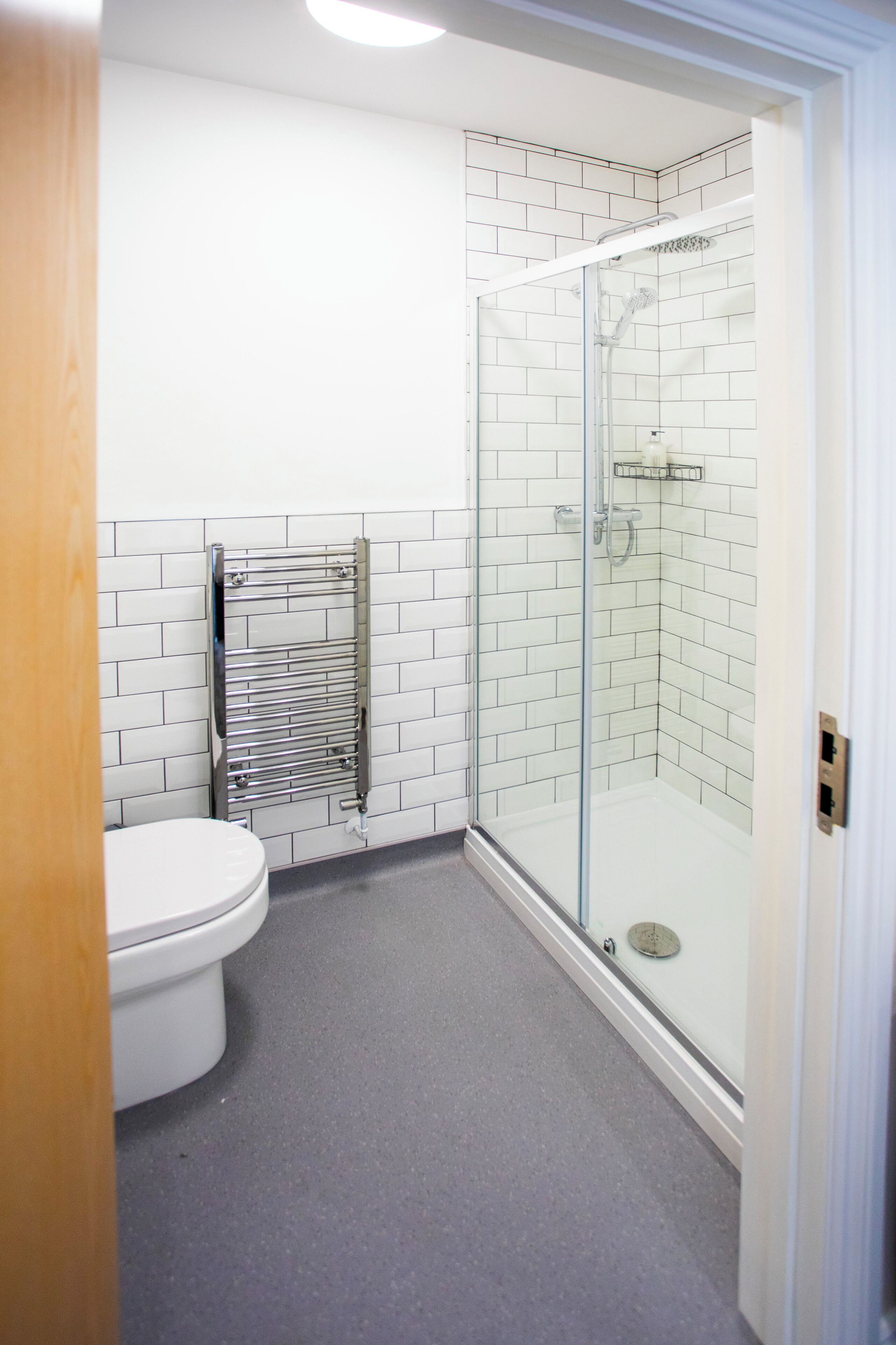 A bathroom with a toilet, a glass shower enclosure, and a towel rack.