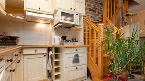Una cocina con armarios blancos, microondas, hervidor y una planta en maceta.