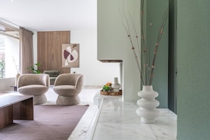 Uma sala de estar moderna com um sofá, uma mesa de centro, um vaso com galhos e uma obra de arte na parede.