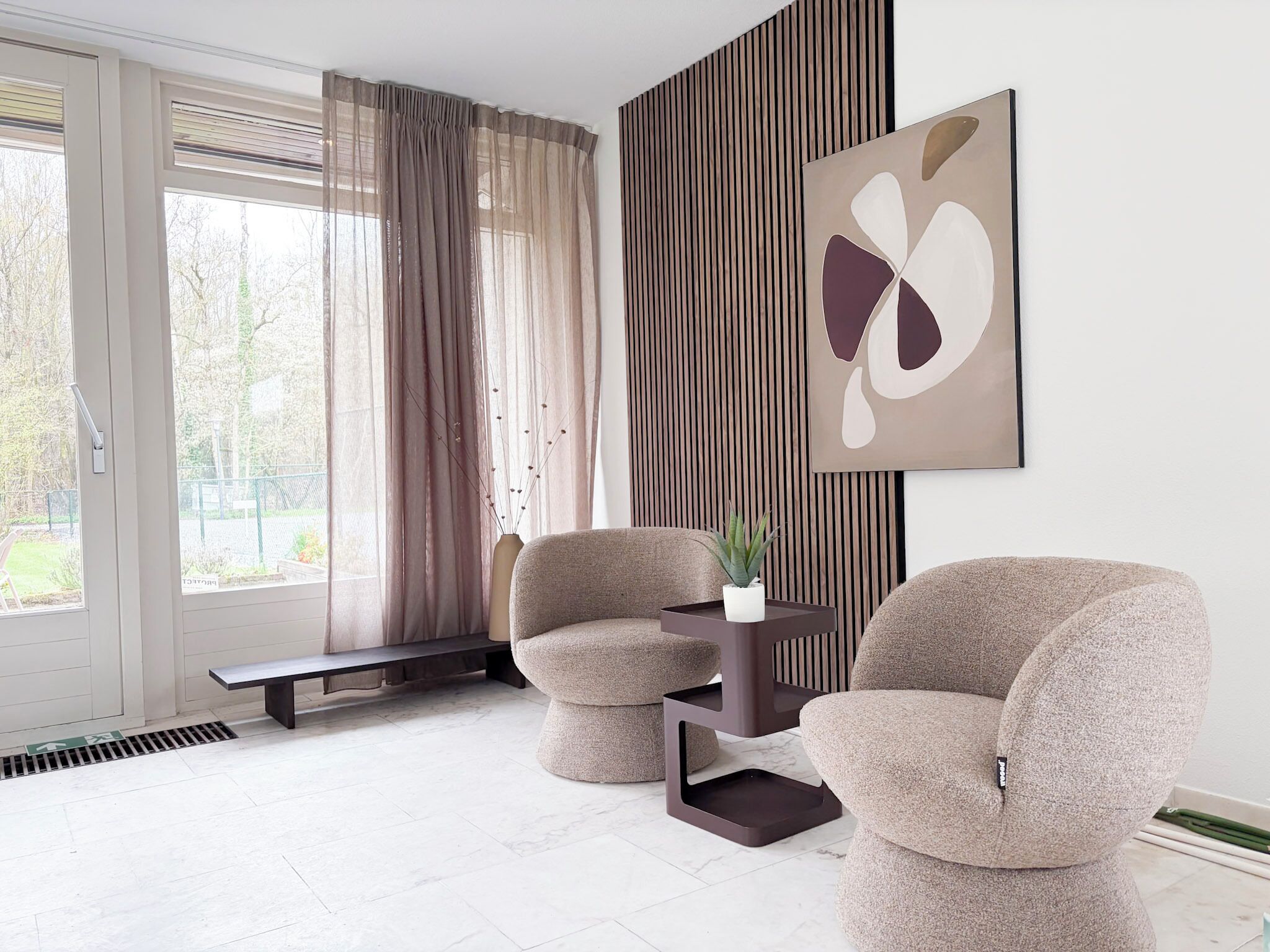 A modern living room with two armchairs, a side table, and a large abstract painting on the wall.